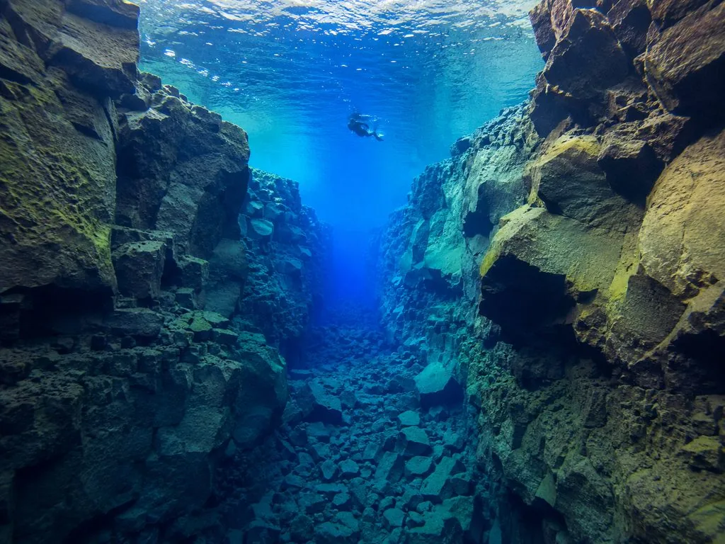 Floating in Silfra Cathedral with canyon walls stretching into the distance